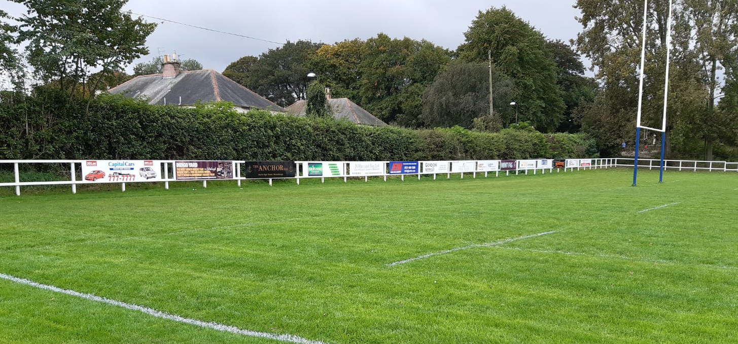 A rugby pitch with many signs next to it