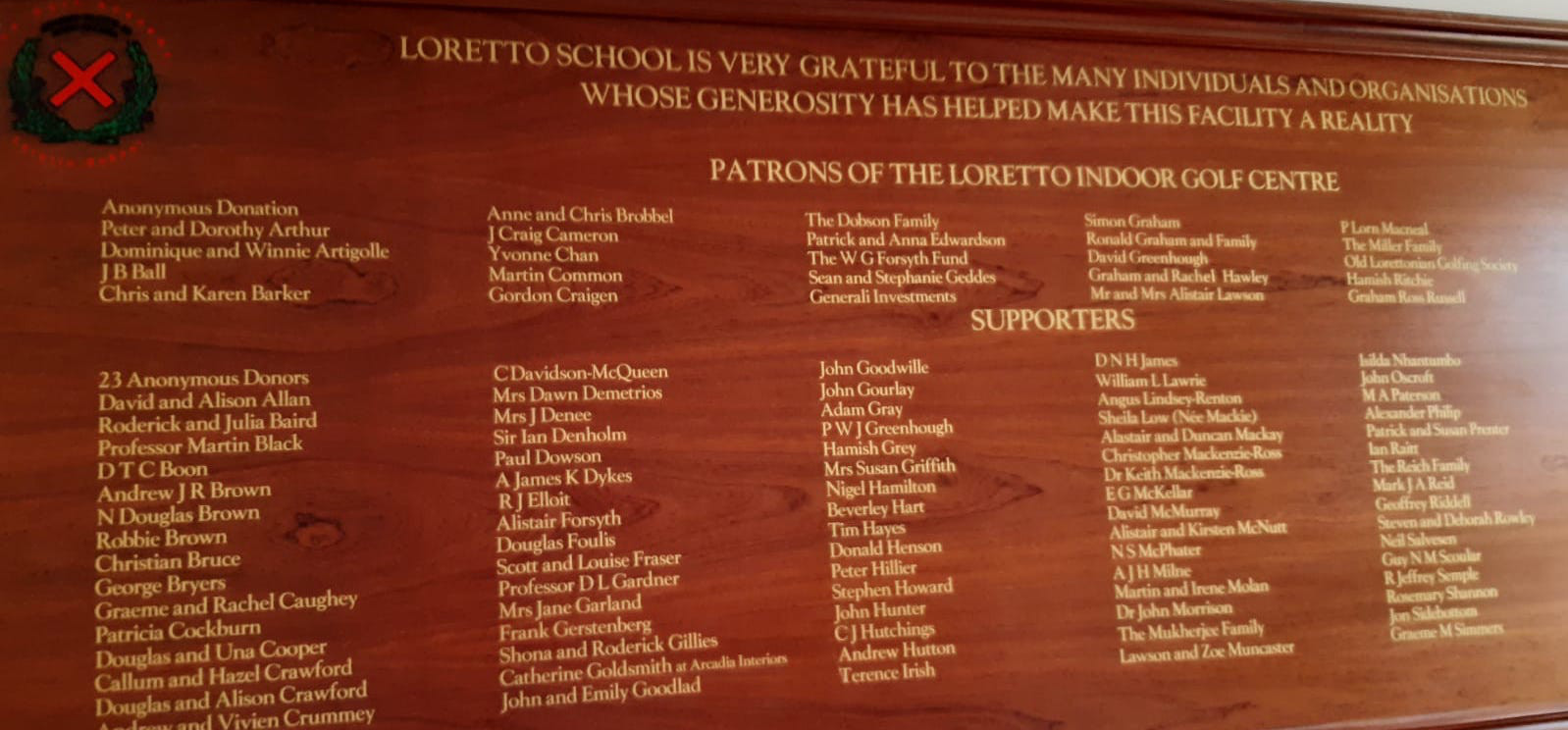 A wooden board with school patrons and supporters writen in gold