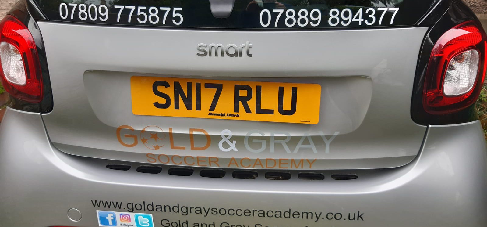 A silver car with gold and gray sign writing